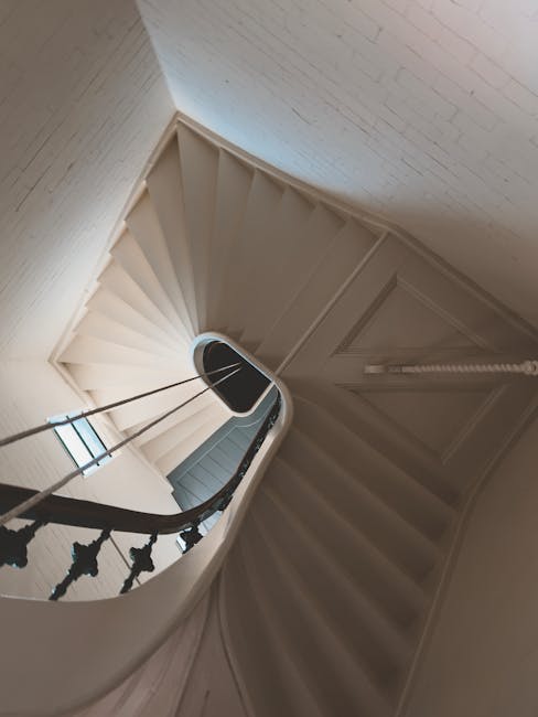 The image shows a staircase inside a residential property, featuring marble steps with visible veining and a dark wooden handrail on the right side, which curves gently at the top. The staircase is il